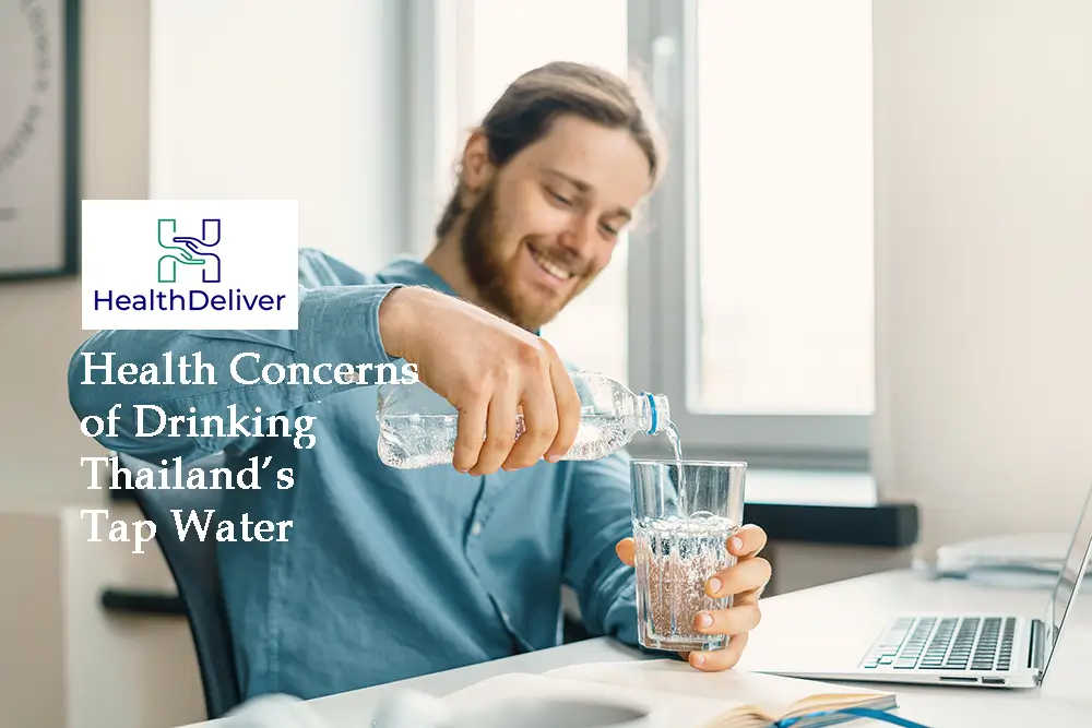 Man pouring tap water into glass at desk with laptop