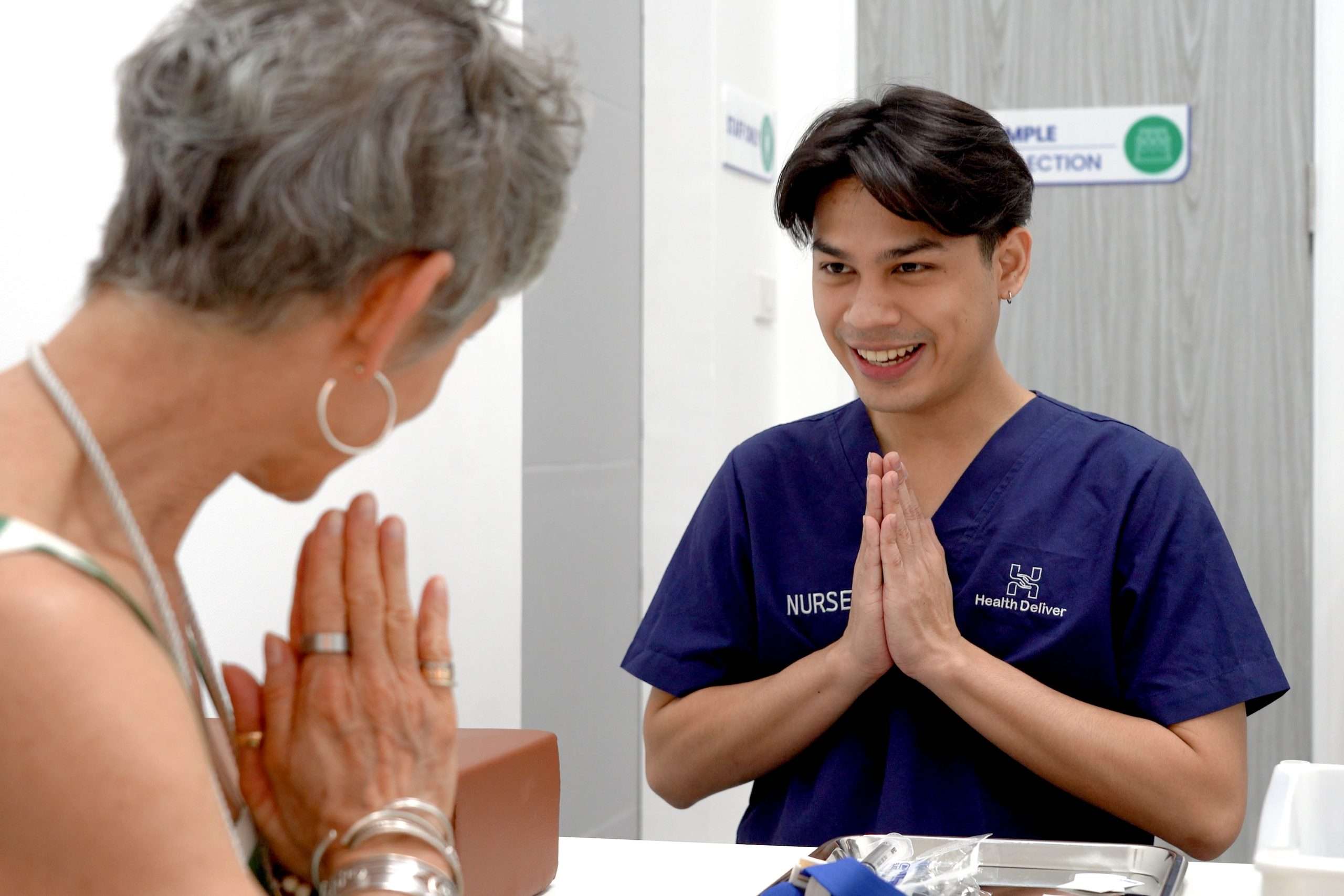 Nurse greeting patient with respectful Thai wai gesture in clinic