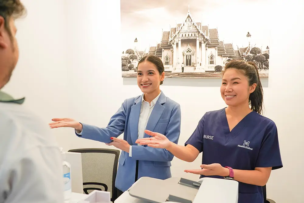 Two healthcare professionals smiling while greeting patient in clinic