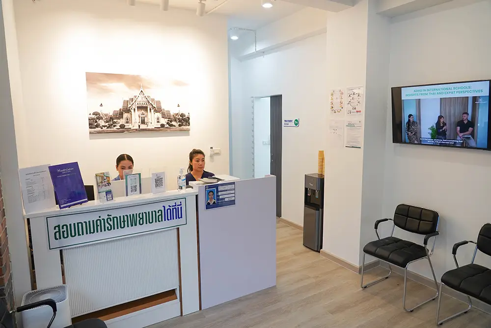 Modern reception desk with Thai text and two staff members in bright office